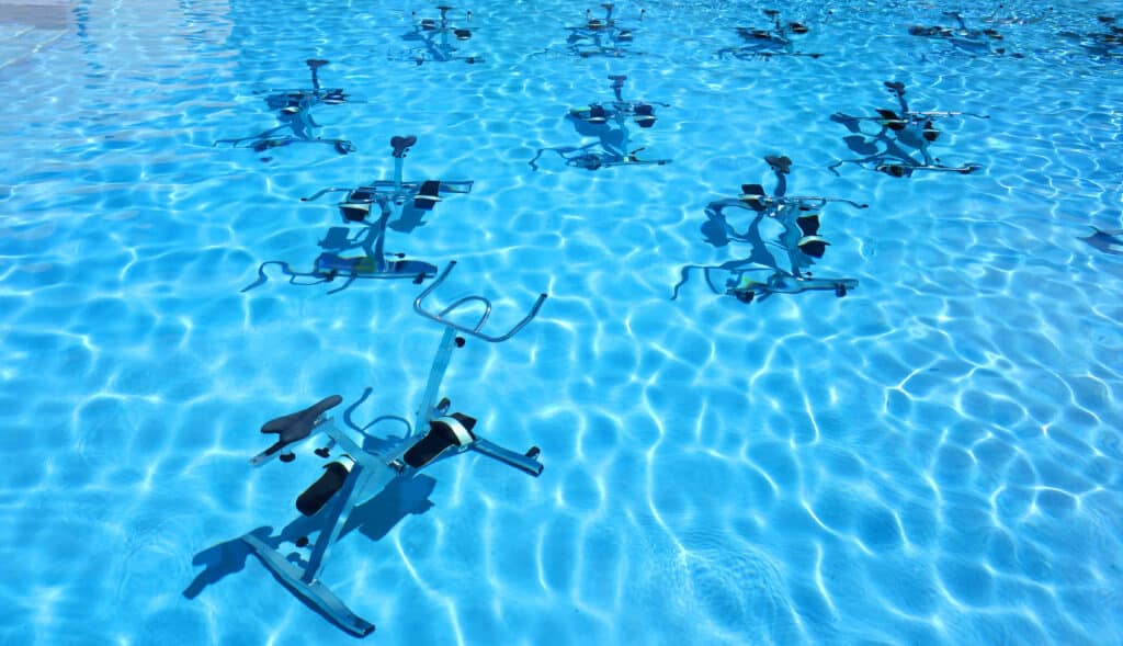 Rangée de vélos aquatiques alignés au fond de la piscine, prêts pour une séance de cours d'aquagym dynamique et efficace.