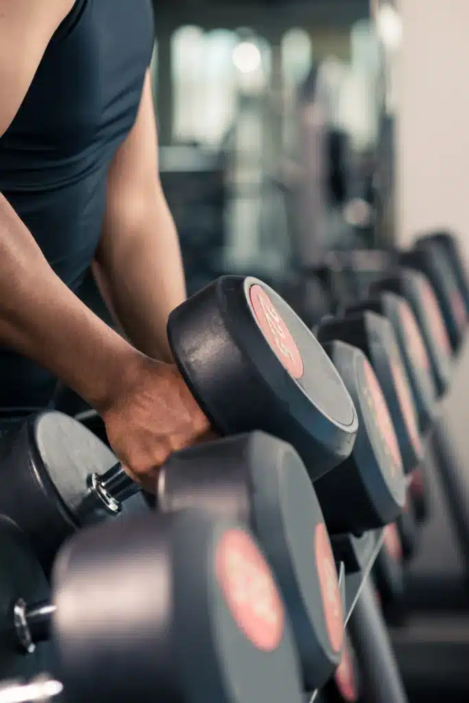 Personne choisissant un haltère lors d'un cours de fitness, mettant l'accent sur l'entraînement de force et l'amélioration de la condition physique.