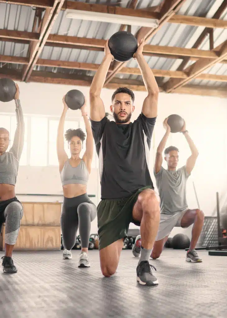 Groupe de participants utilisant des medecine balls dans un cours de fitness dynamique, ciblant l'endurance et la coordination.