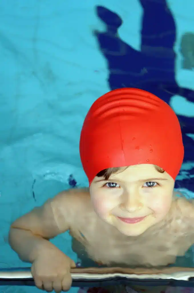 Bébé accompagné par ses parents et une instructrice pendant un cours de natation, introduisant les tout-petits au plaisir de l'eau.