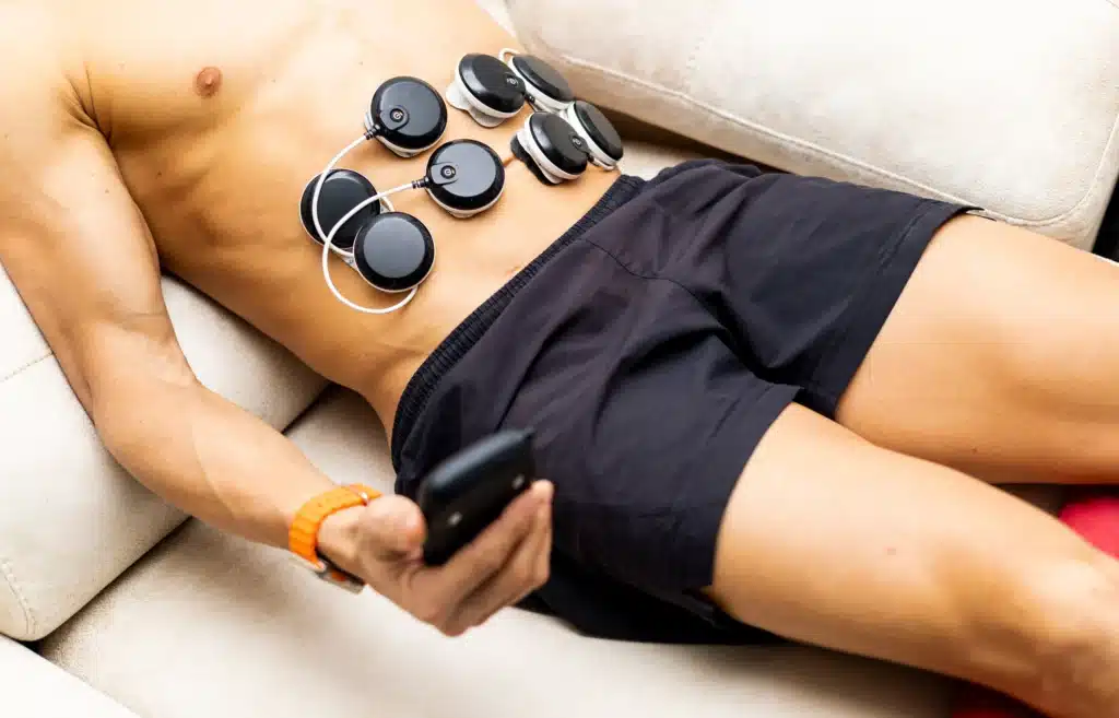 Homme utilisant des électrodes pour une séance d'électrostimulation abdominale pendant un cours de fitness.